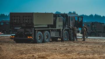 Samoch&oacute;d ciężarowy z zamontowanym systemem rakietowym na tle lasu.