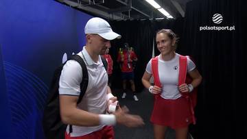 Mężczyzna i kobieta w strojach tenisowych rozmawiają i uśmiechają się, oboje mają plecaki tenisowe.