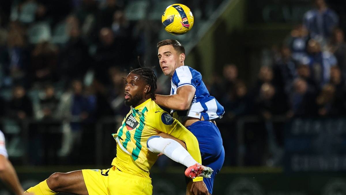 Dwóch piłkarzy walczy o piłkę w powietrzu podczas meczu.