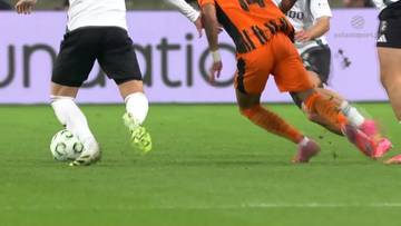 Dwaj piłkarze walczący o piłkę na zielonym boisku podczas meczu.