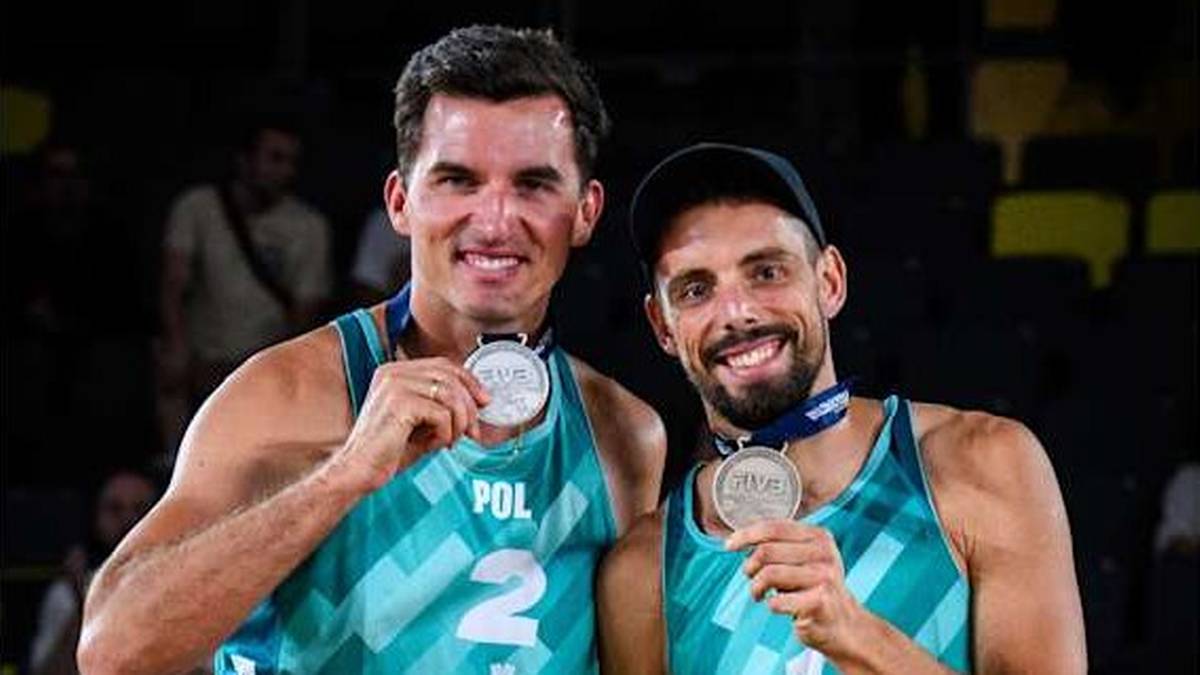 Dwóch siatkarzy plażowych, Michał Bryl i Bartosz Łosiak, prezentuje zdobyte medale.