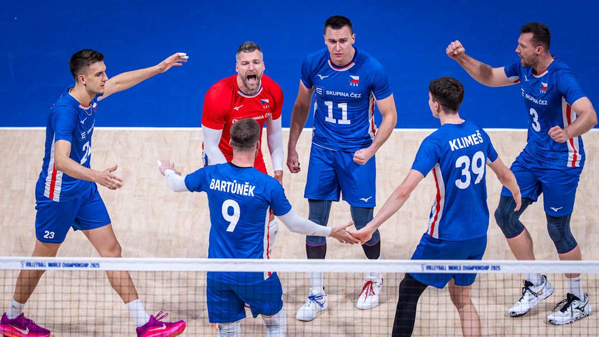 Grupa siatkarzy w niebieskich strojach świętuje zwycięstwo na boisku siatkarskim, niektórzy z nich unoszą ręce w geście radości.