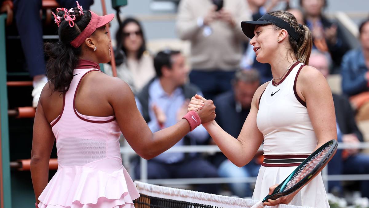 Dwie tenisistki, jedna w różowym stroju, druga w białym, uścisnęły sobie dłonie nad siatką po meczu na korcie.