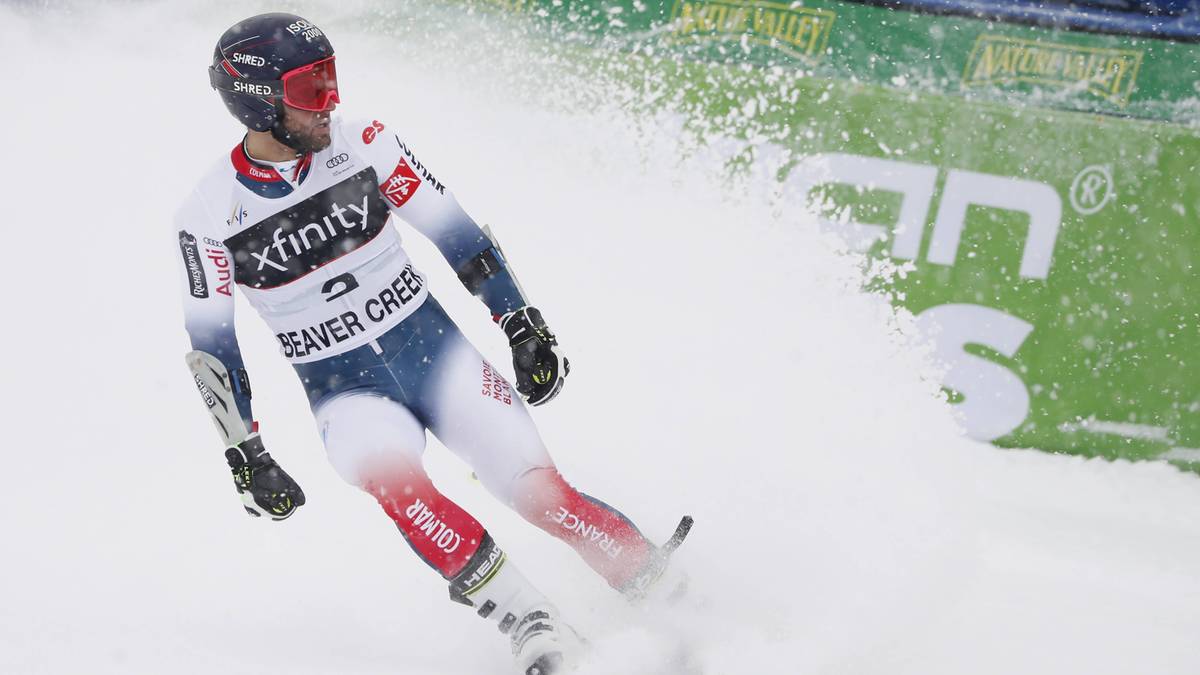 Narciarz alpejski zjeżdża po stoku, wzbijając śnieg