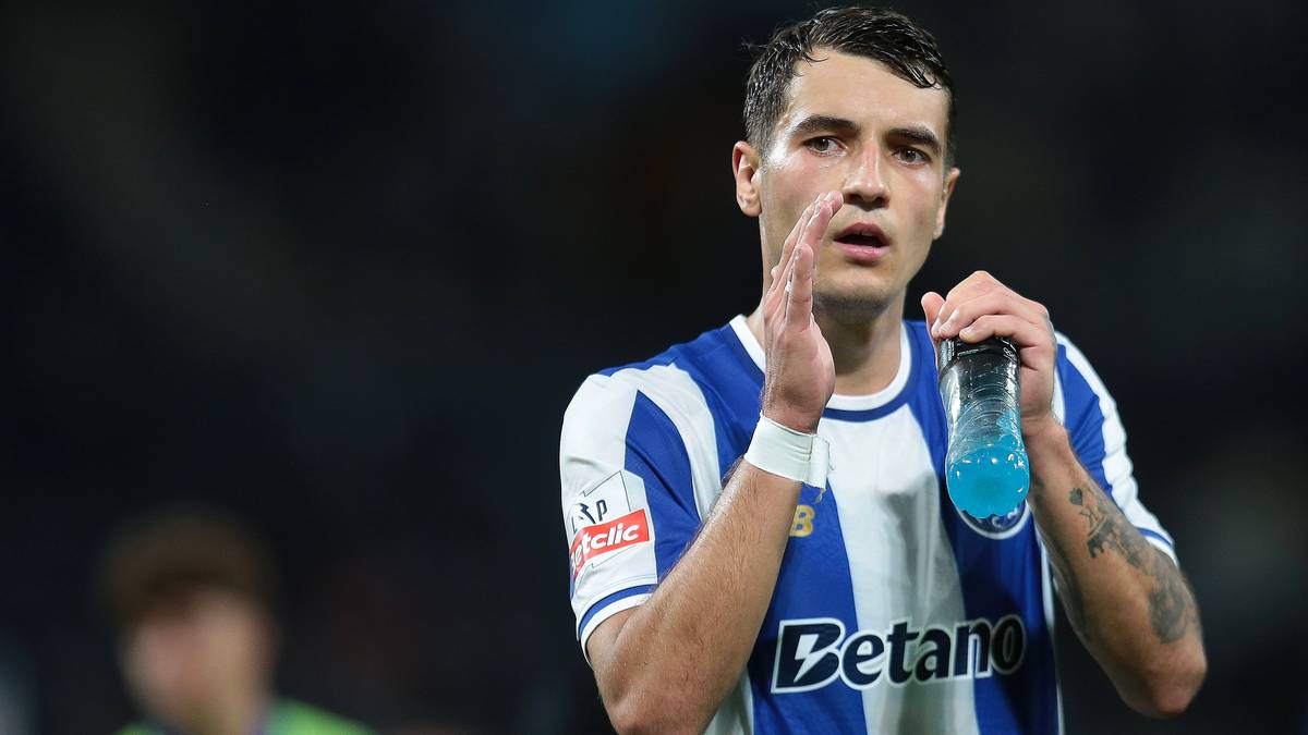 Piłkarz Jakub Kiwior w niebiesko-białej koszulce FC Porto, z butelką niebieskiego napoju w dłoni.