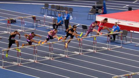 Zawodnicy pokonujący płotki podczas biegu lekkoatletycznego.