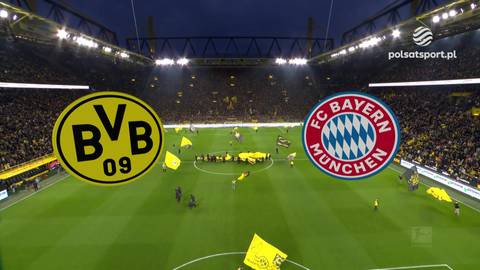 Herby Borussii Dortmund i Bayernu Monachium na środku boiska piłkarskiego, w tle trybuny pełne kibic&oacute;w.
