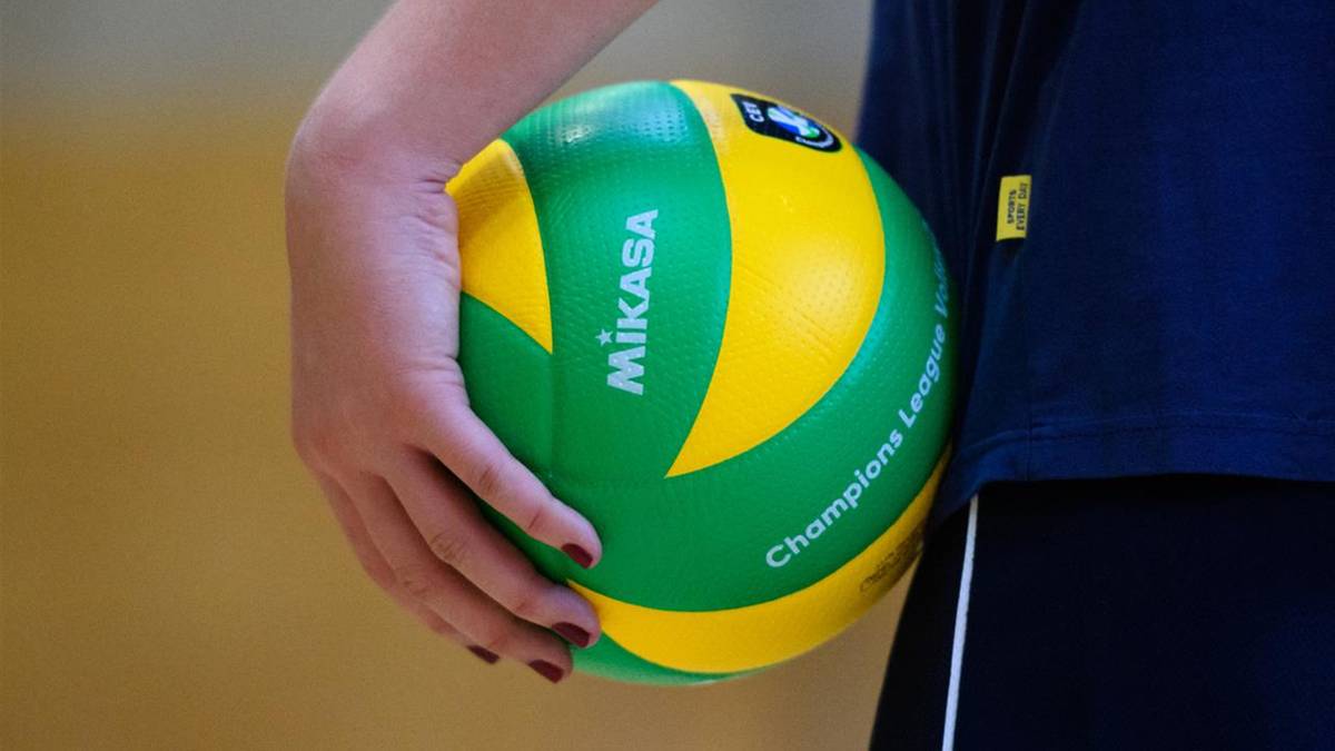 Dłoń trzyma piłkę do siatk&oacute;wki Mikasa w kolorach zielonym i ż&oacute;łtym.