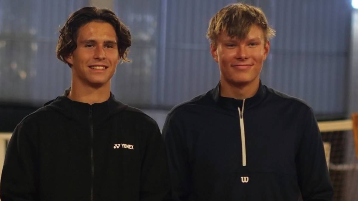 Dwóch młodych mężczyzn w strojach sportowych stoi obok siebie i uśmiecha się do kamery.