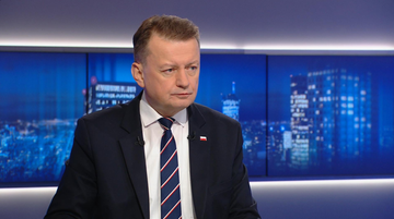 Mariusz Błaszczak, wiceprezes Prawa i Sprawiedliwości, ubrany w garnitur i krawat, siedzi w studiu telewizyjnym.