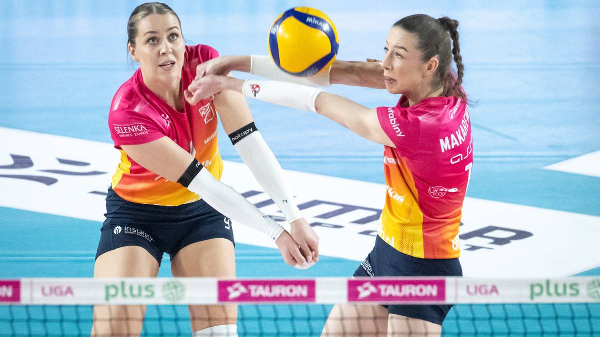 Dwie siatkarki walczą o przyjęcie piłki podczas meczu siatk&oacute;wki.