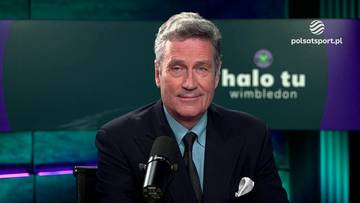 Mężczyzna w garniturze, siedzący przed mikrofonem, z logo Polsat Sport i napisem "halo tu wimbledon" na tle.