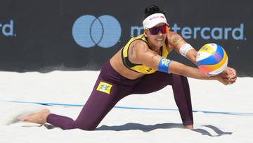 Siatkarka plażowa w pozycji obronnej, przyjmująca piłkę na piasku.