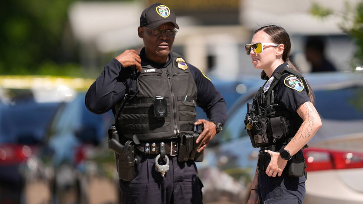 Dw&oacute;ch policjant&oacute;w w mundurach, mężczyzna i kobieta, stojący na zewnątrz i rozmawiający.