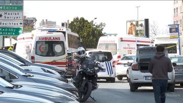 Widok ulicy w Stambule z kilkoma zaparkowanymi samochodami, motocyklem policyjnym i dwoma ambulansami w tle. Na znakach drogowych widnieje napis "Besiktas".