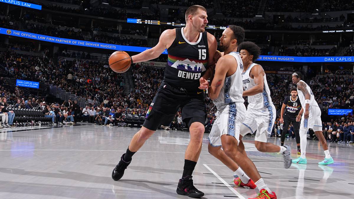 Koszykarz Nikola Jokić w czarnej koszulce z numerem 15 na plecach, trzymający piłkę, w akcji podczas meczu koszyk&oacute;wki.