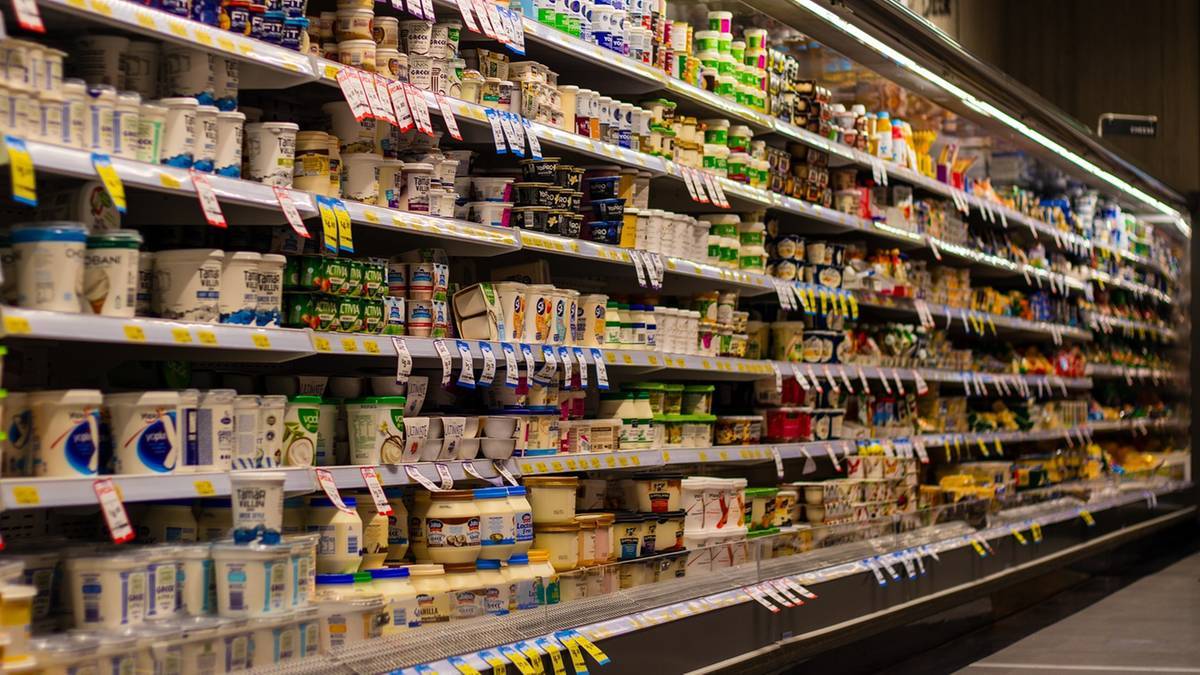 Zdjęcie przedstawia regały sklepowe z produktami spożywczymi, w tym nabiałem.