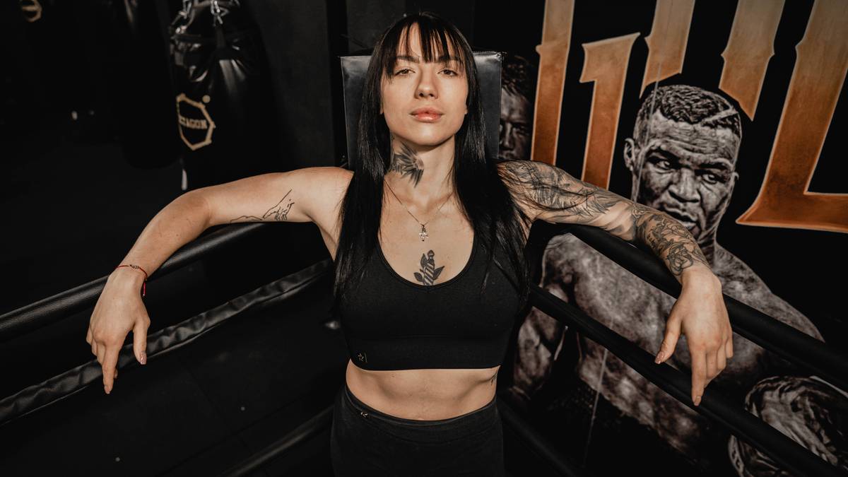 Kobieta bokserka w czarnym topie i z tatuażami stoi w ringu