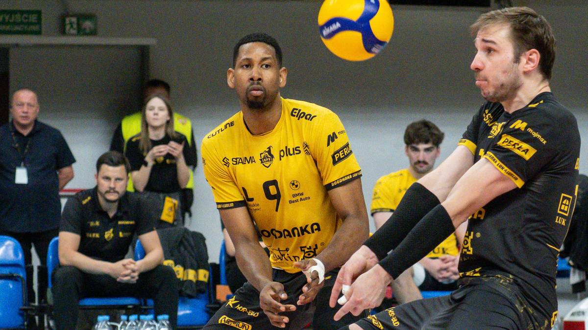 Dw&oacute;ch siatkarzy w ż&oacute;łtych koszulkach podczas meczu, jeden z nich pr&oacute;buje zagrać piłkę.