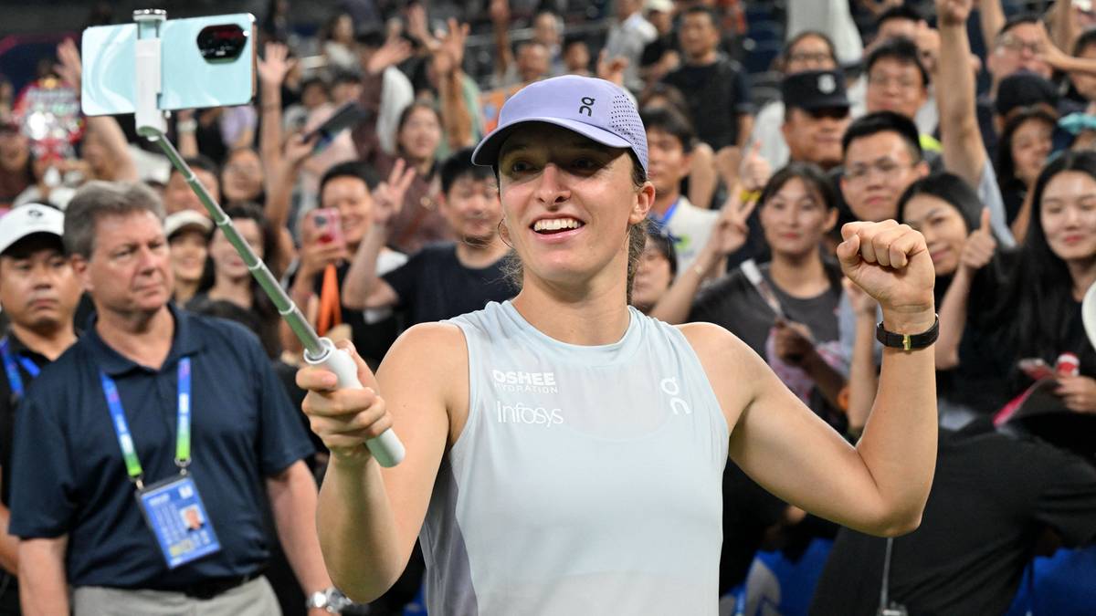 Iga Świątek robi sobie zdjęcie selfie z fanami, uśmiechając się do telefonu.