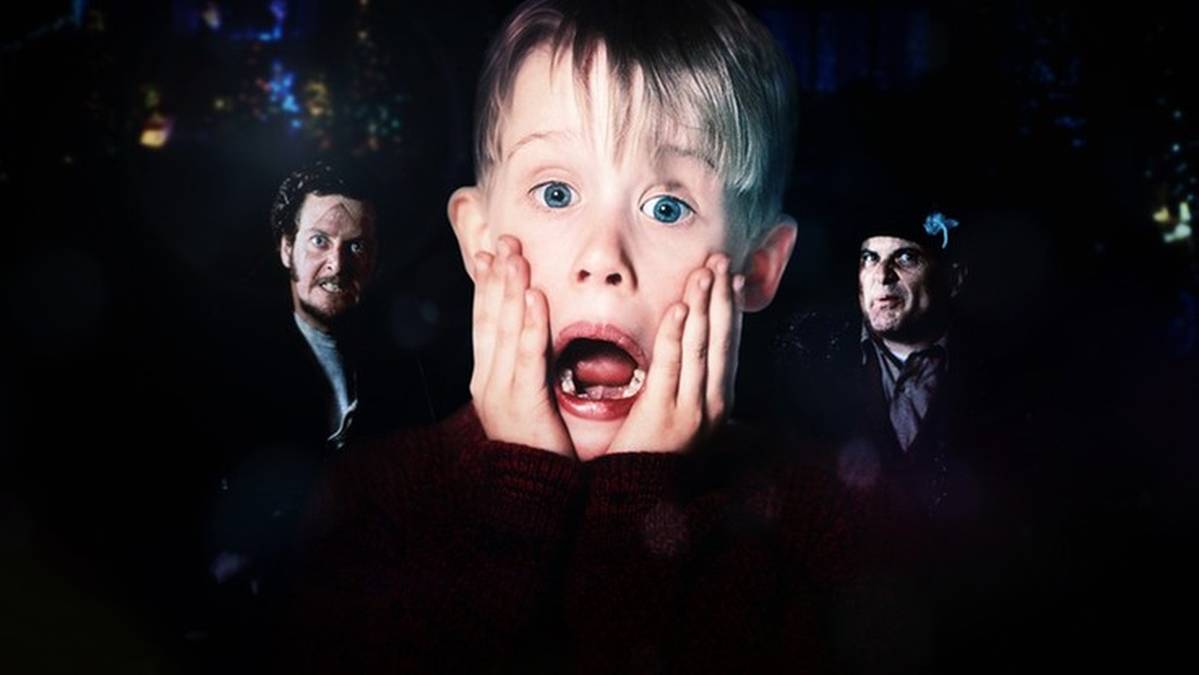 Zbliżenie na twarz chłopca z szeroko otwartymi ustami i dłońmi przy policzkach, otoczonego przez dw&oacute;ch mężczyzn.