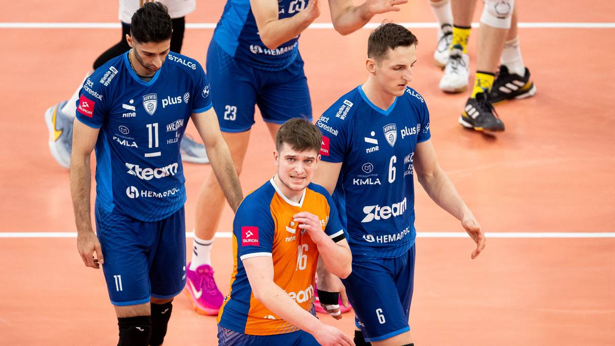 Siatkarze w niebieskich strojach schodzą z boiska po przegranym meczu.