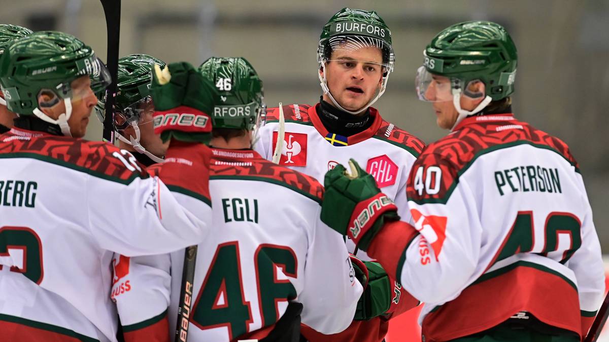 Grupa hokeist&oacute;w w zielonych kaskach i białych strojach świętuje na lodowisku.