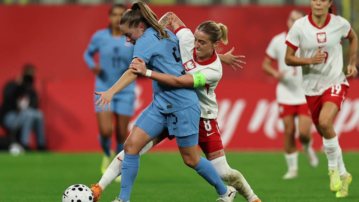 Piłkarka w niebieskim stroju walczy o piłkę z zawodniczką w białej koszulce z polskimi barwami.