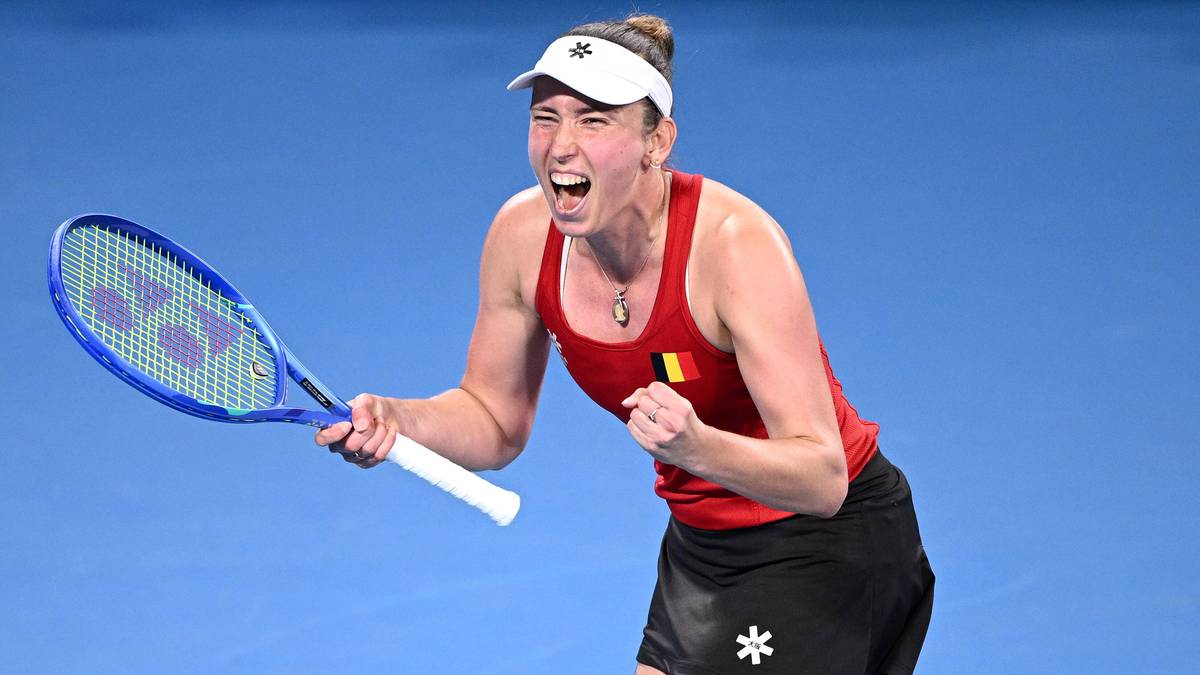 Tenisistka w czerwonej koszulce i czarnej sp&oacute;dniczce świętuje zdobycie punktu, trzymając rakietę tenisową.