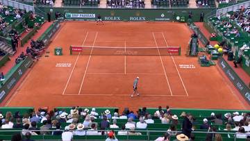 Kort tenisowy z zawodnikiem i widzami.