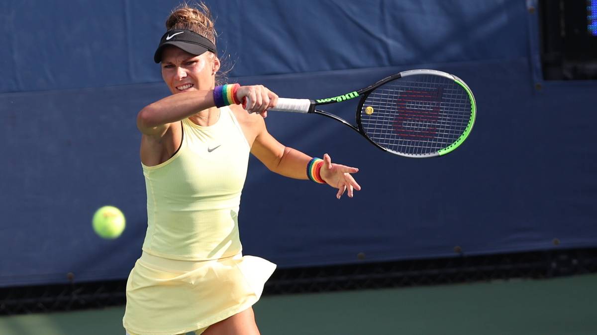 Młoda kobieta w stroju tenisowym uderza piłkę rakietą podczas meczu.