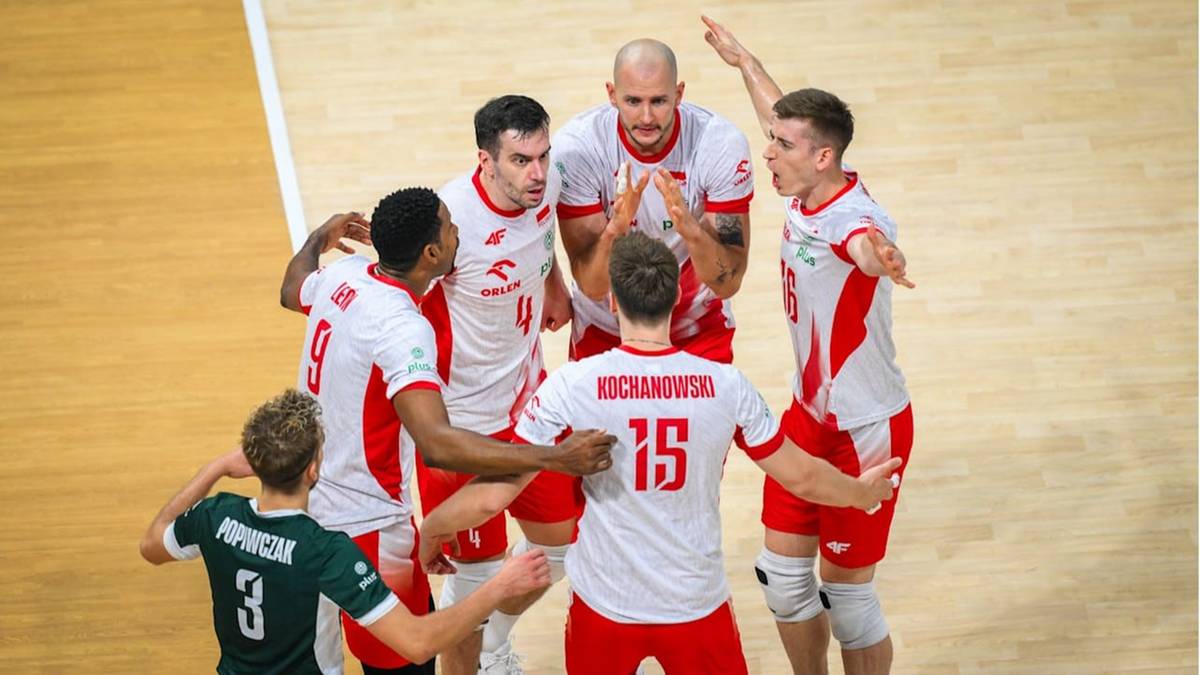 Drużyna siatkarzy w białych strojach świętuje zwycięstwo, otaczając zawodnika z numerem 15.