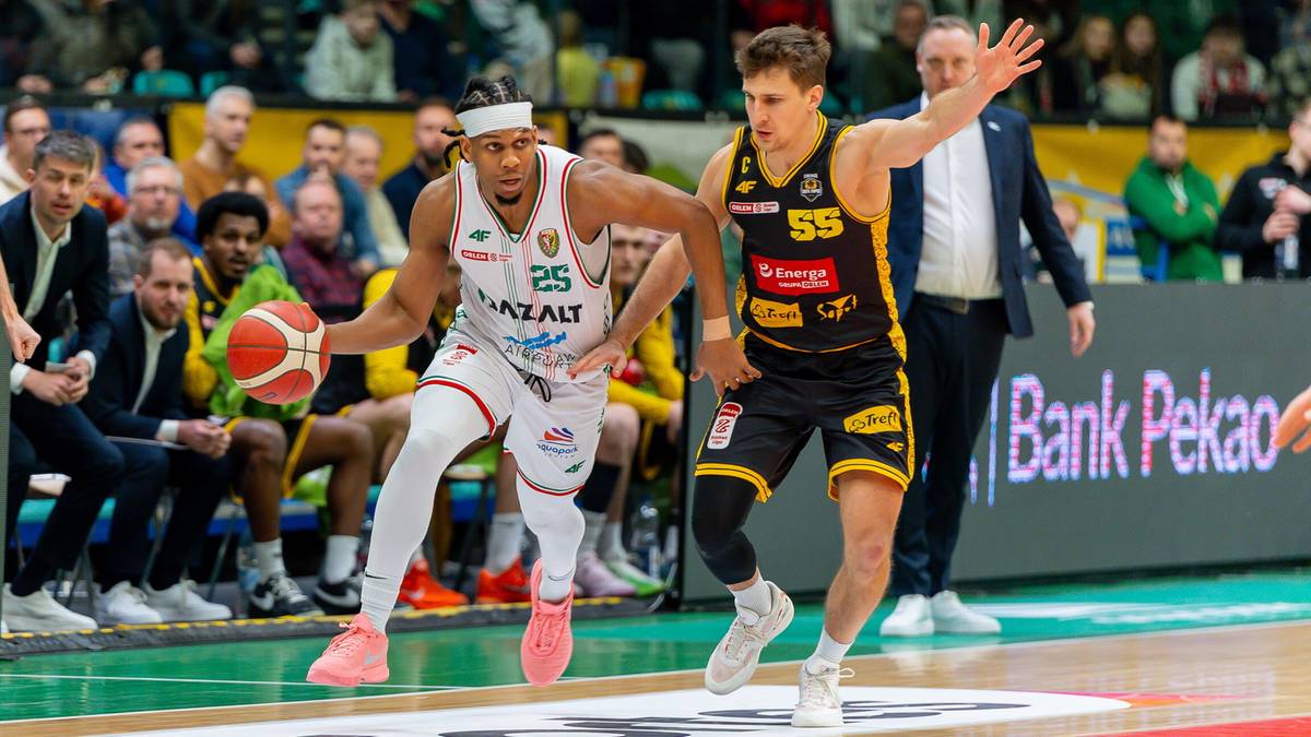 Dwóch koszykarzy podczas meczu koszykówki, jeden z piłką, drugi broniący.