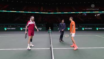 Dw&oacute;ch tenisist&oacute;w, Hubert Hurkacz i Alexander Bublik, stoi naprzeciw siebie na zielonym korcie tenisowym podczas meczu. Obaj trzymają rakiety, a w tle widać publiczność i bandy reklamowe.