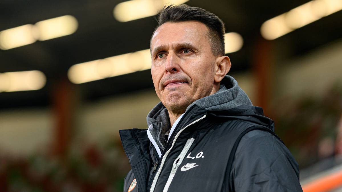 Portret mężczyzny w stroju sportowym, prawdopodobnie trenera lub piłkarza, patrzącego w bok.