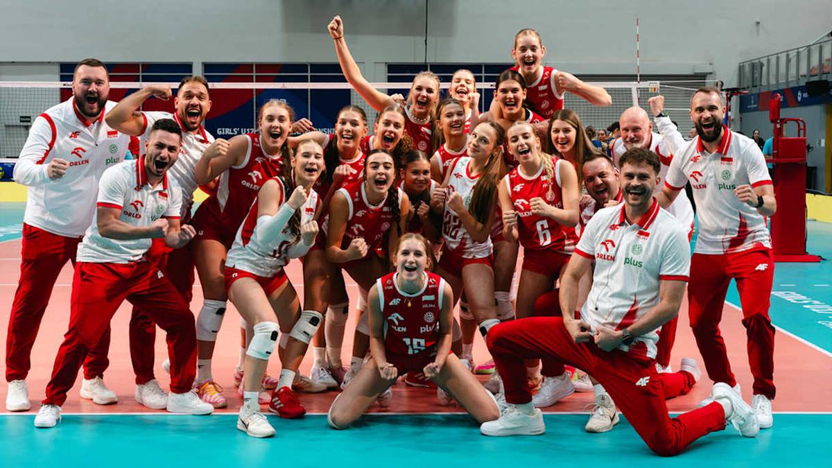 Uśmiechnięta drużyna siatkarska, złożona z kobiet i mężczyzn w czerwono-białych strojach sportowych, pozuje razem po meczu.