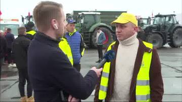 Dziennikarz w słuchawkach i kamizelce odblaskowej trzyma mikrofon w kierunku rolnika w żółtej czapce i kamizelce odblaskowej. W tle stoją ciągniki.