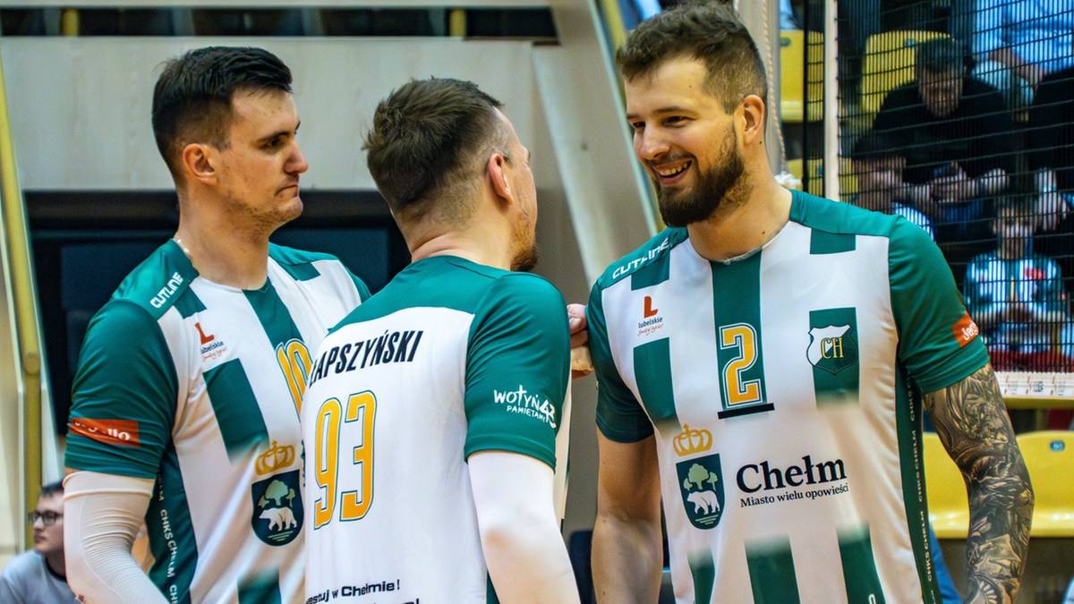 Trzech siatkarzy w zielono-białych koszulkach ChKS rozmawia po meczu, okazując radość i entuzjazm.
