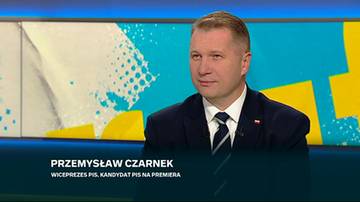 Przemysław Czarnek w garniturze i krawacie podczas wypowiedzi telewizyjnej na tle niebiesko-ż&oacute;łtej scenografii.