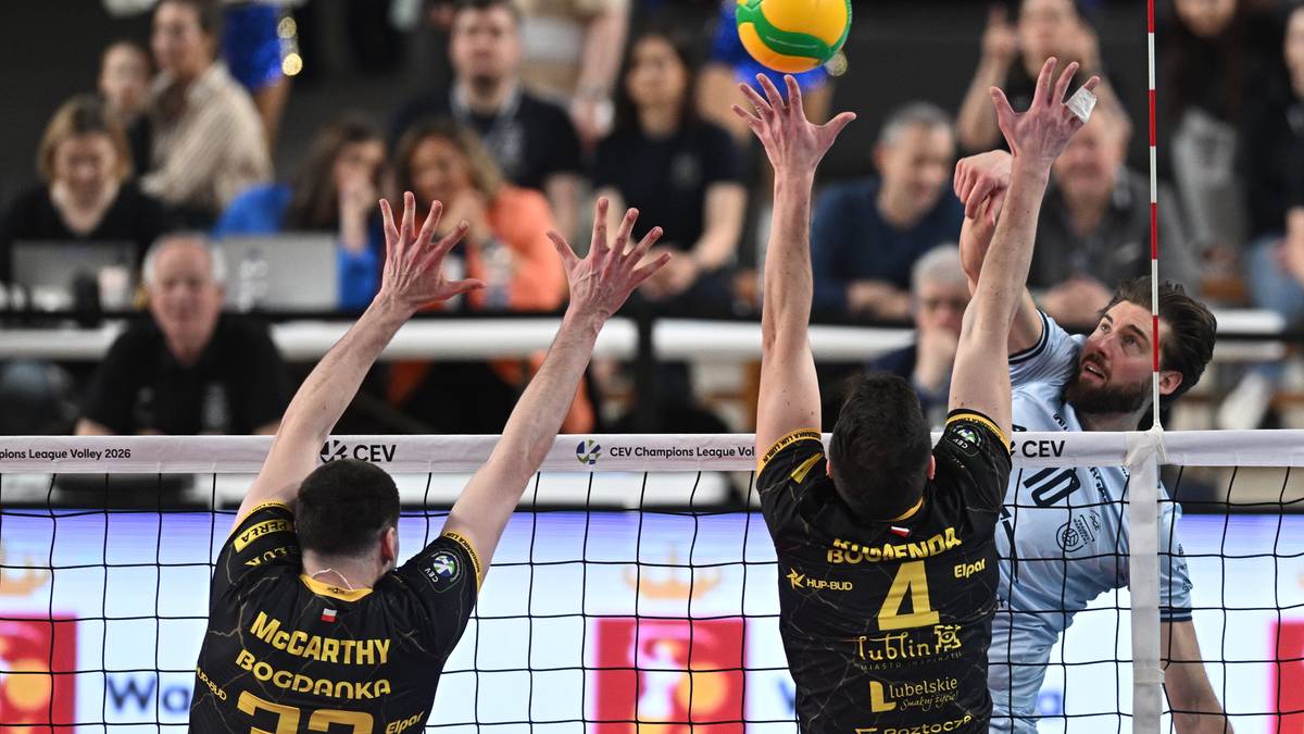 Dw&oacute;ch siatkarzy pr&oacute;buje zablokować piłkę nad siatką w trakcie meczu siatk&oacute;wki.