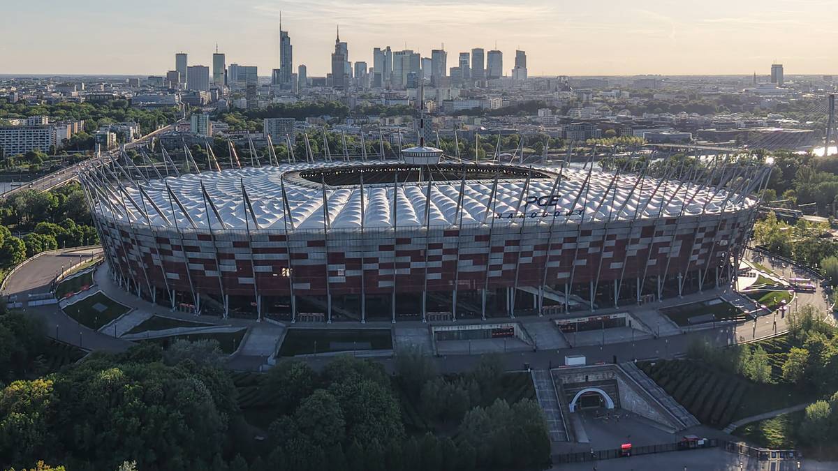 Widok z lotu ptaka na Stadion Narodowy w Warszawie, z panoramą miasta w tle.
