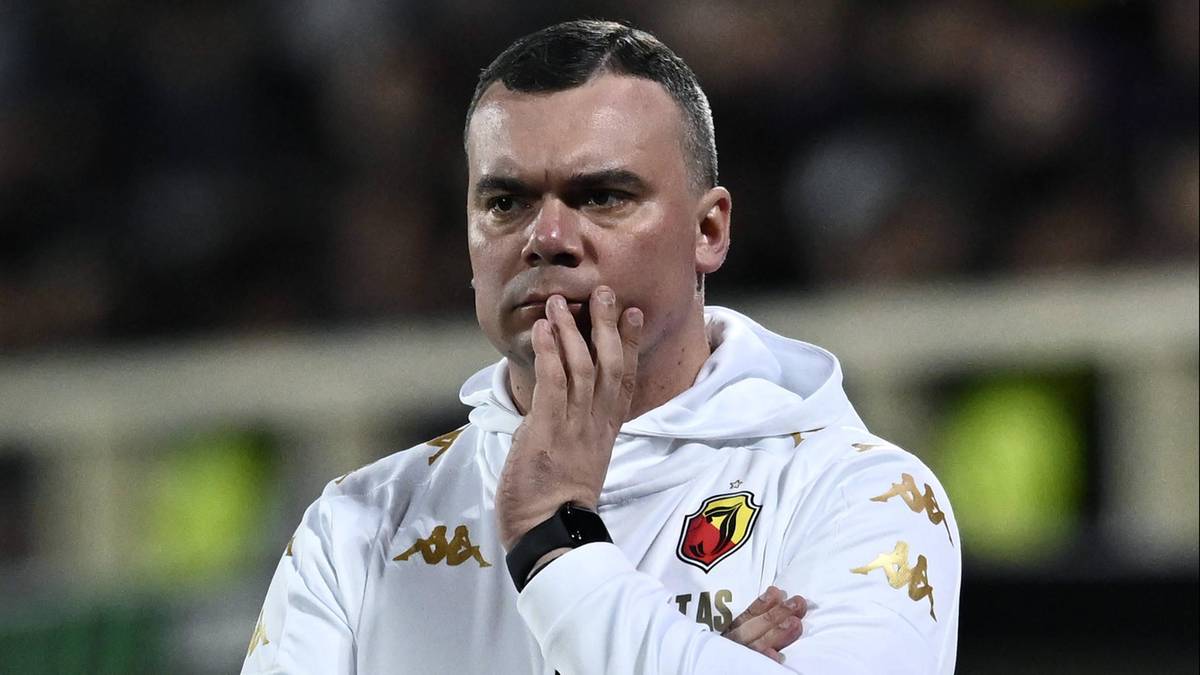 Trener Jagiellonii Białystok w białej bluzie z kapturem zamyślony