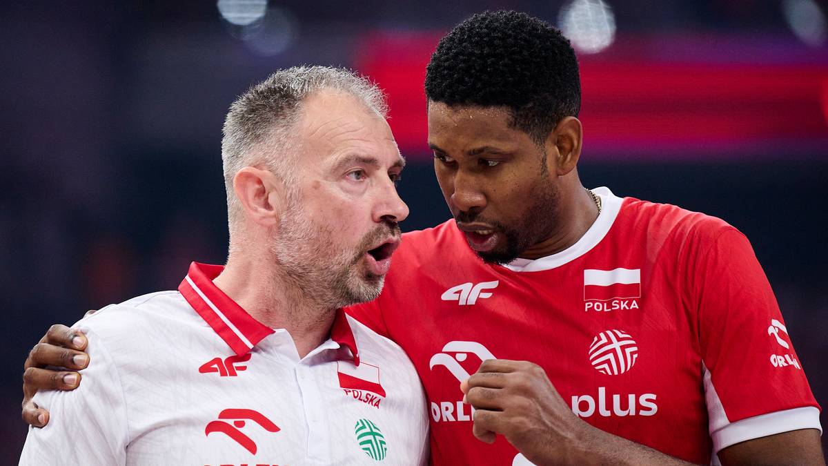 Dw&oacute;ch mężczyzn w strojach sportowych rozmawia, jeden gestykuluje, drugi słucha.