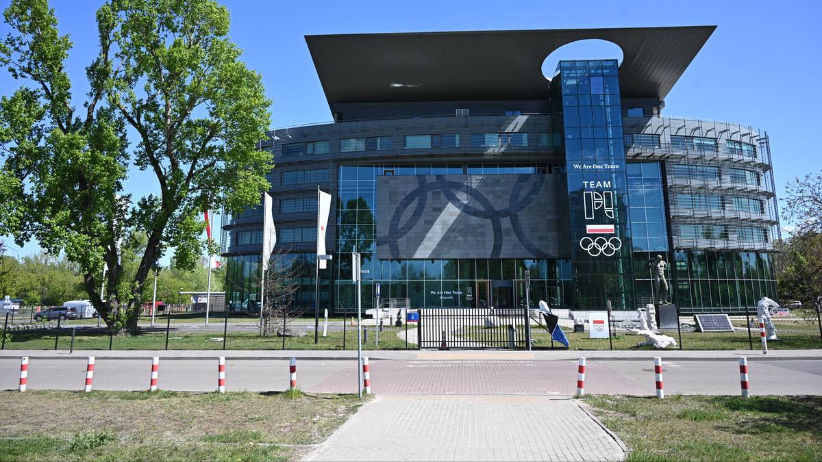 Budynek Polskiego Komitetu Olimpijskiego z logotypem "TEAM POLSKA" i pierścieniami olimpijskimi na fasadzie.