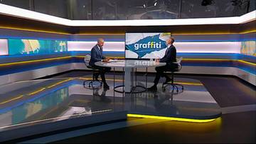 Dw&oacute;ch mężczyzn w garniturach siedzi przy stole w nowoczesnym studiu telewizyjnym programu Graffiti.