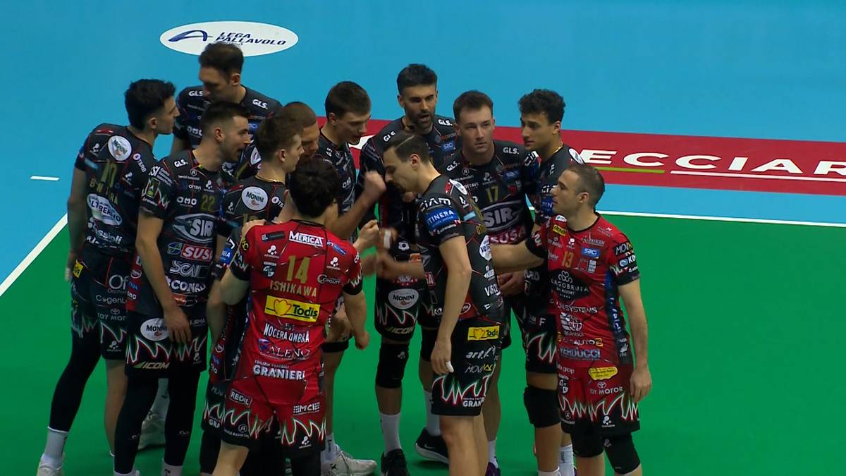 Siatkarze w strojach sportowych zebrani w kręgu na boisku siatkarskim.