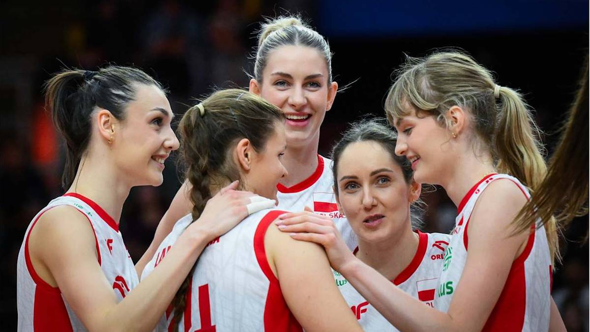 Pięć zawodniczek w białych strojach sportowych z czerwonymi detalami, patrzących na siebie z uśmiechem.