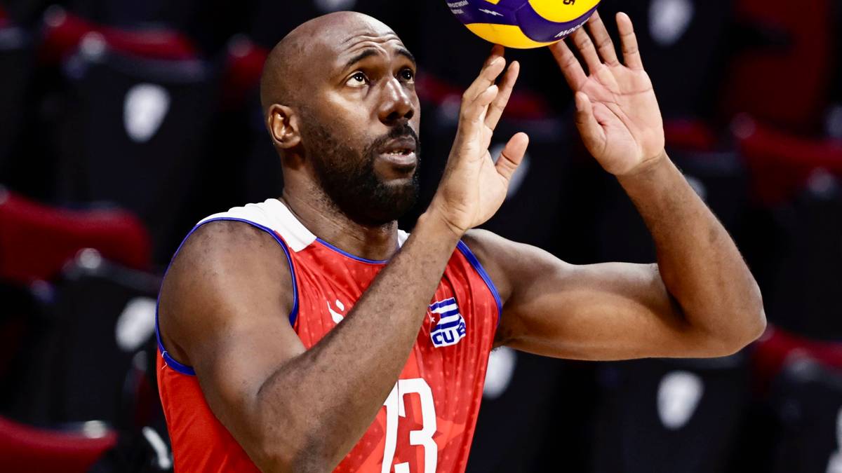 Siatkarz w czerwonej koszulce z numerem 3, trzymający piłkę do siatk&oacute;wki nad głową.