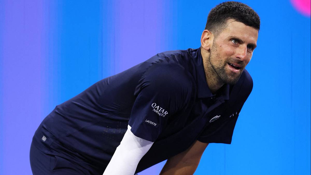 Novak Djoković pochyla się na korcie tenisowym, opierając ręce na kolanach i trzymając rakietę.