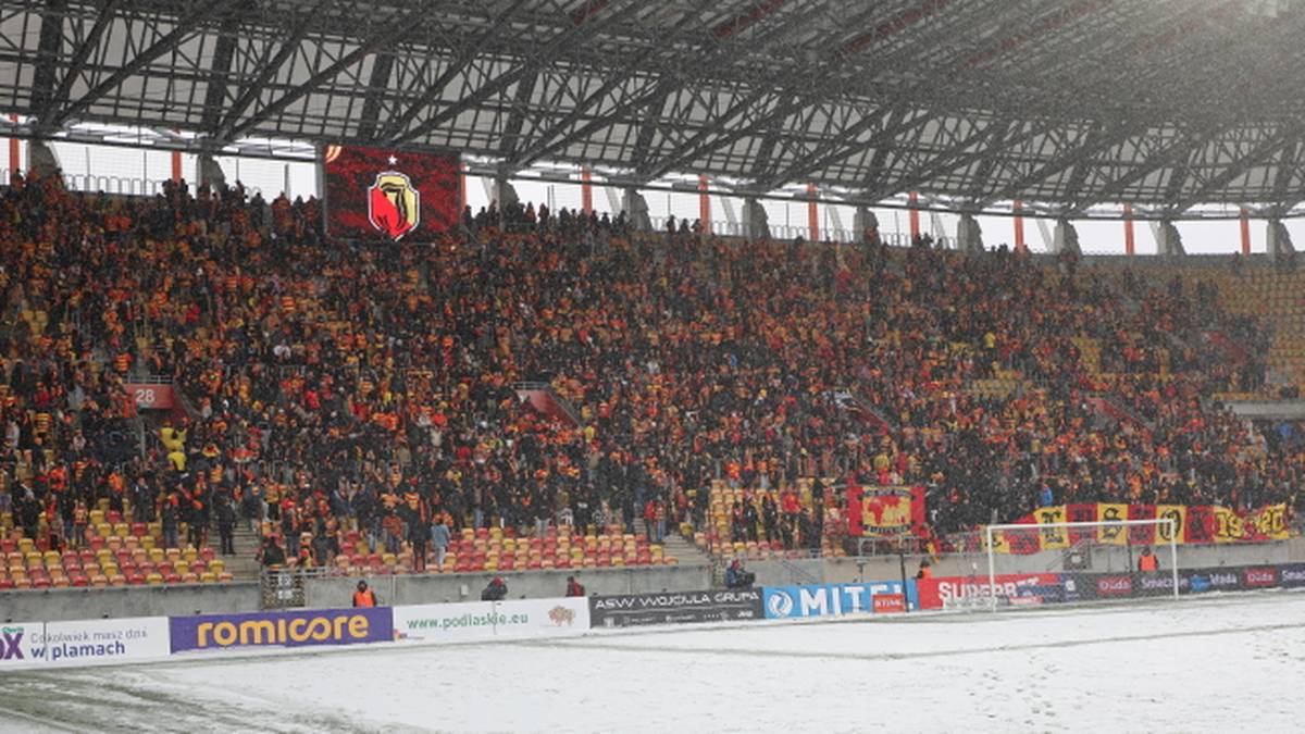 Widok na zapełnione trybuny stadionu piłkarskiego z kibicami w zimowej scenerii.